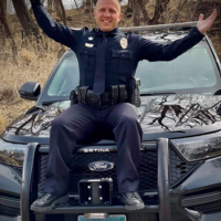 Brad Schenck sitting on the top of his police car hood.